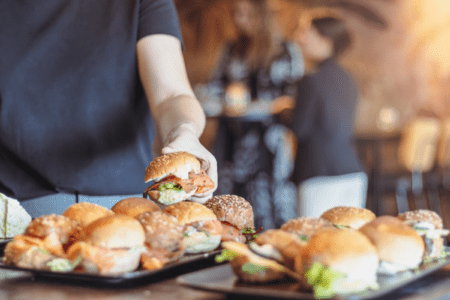 Broodjes tijdens lunch waarbij een deelnemer een broodje pakt bij zakelijke bijeenkomst